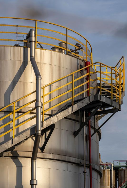 a large corrosive stainless steel tank with stairs leading up to it .