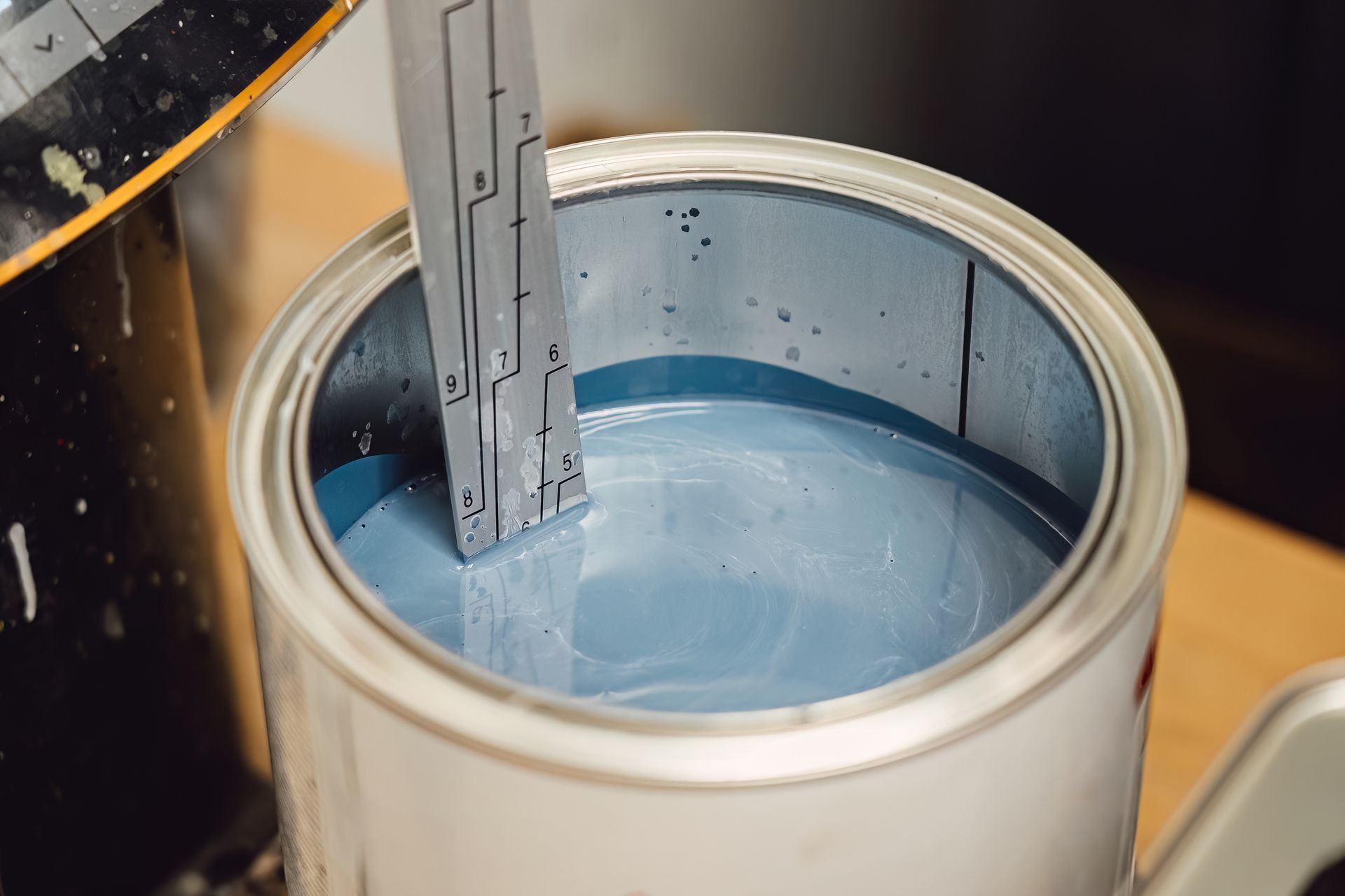 Open can of blue liquid with a metal stirrer inside