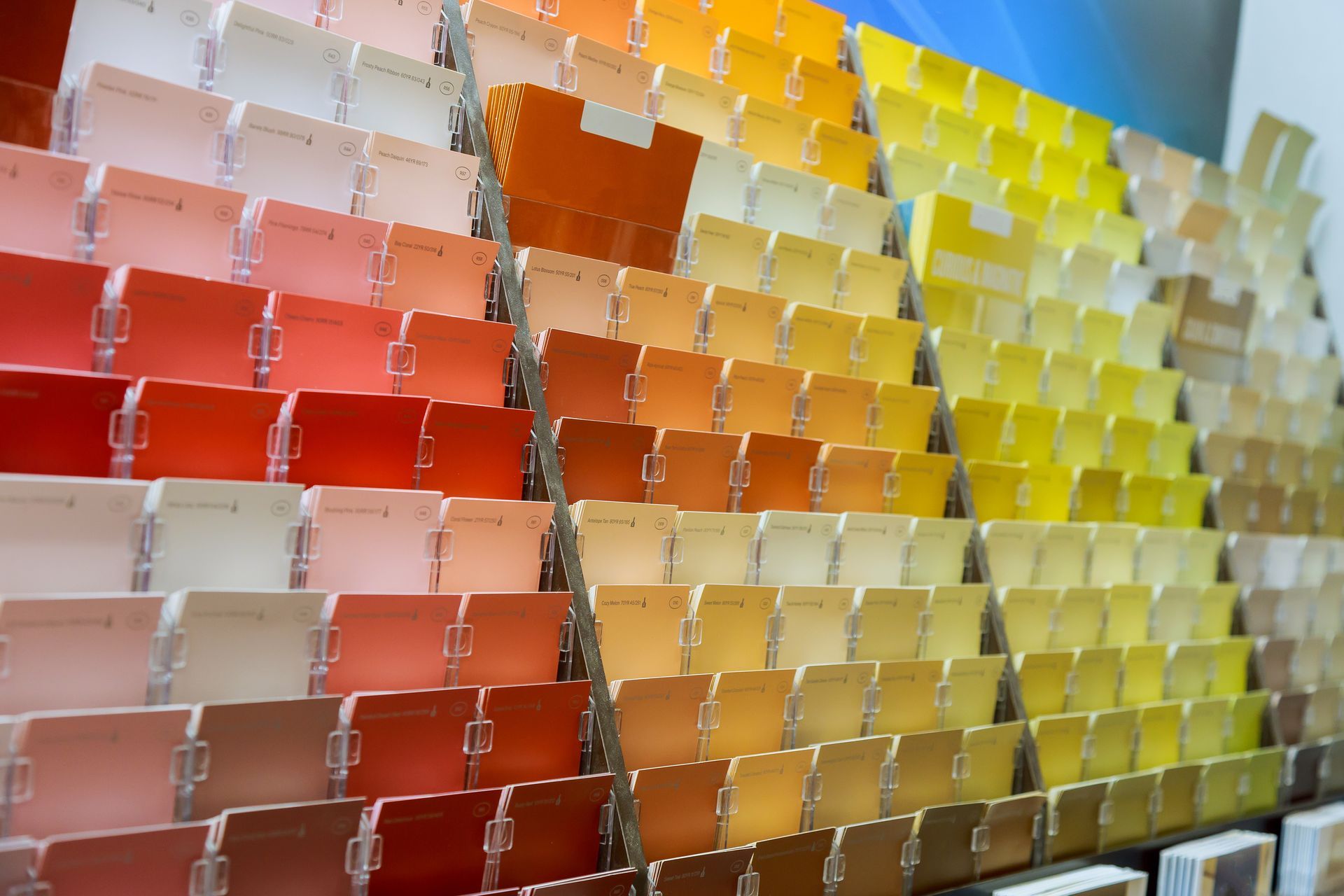 Rows of colorful folded cards or samples arranged in a gradient from red to yellow on display racks