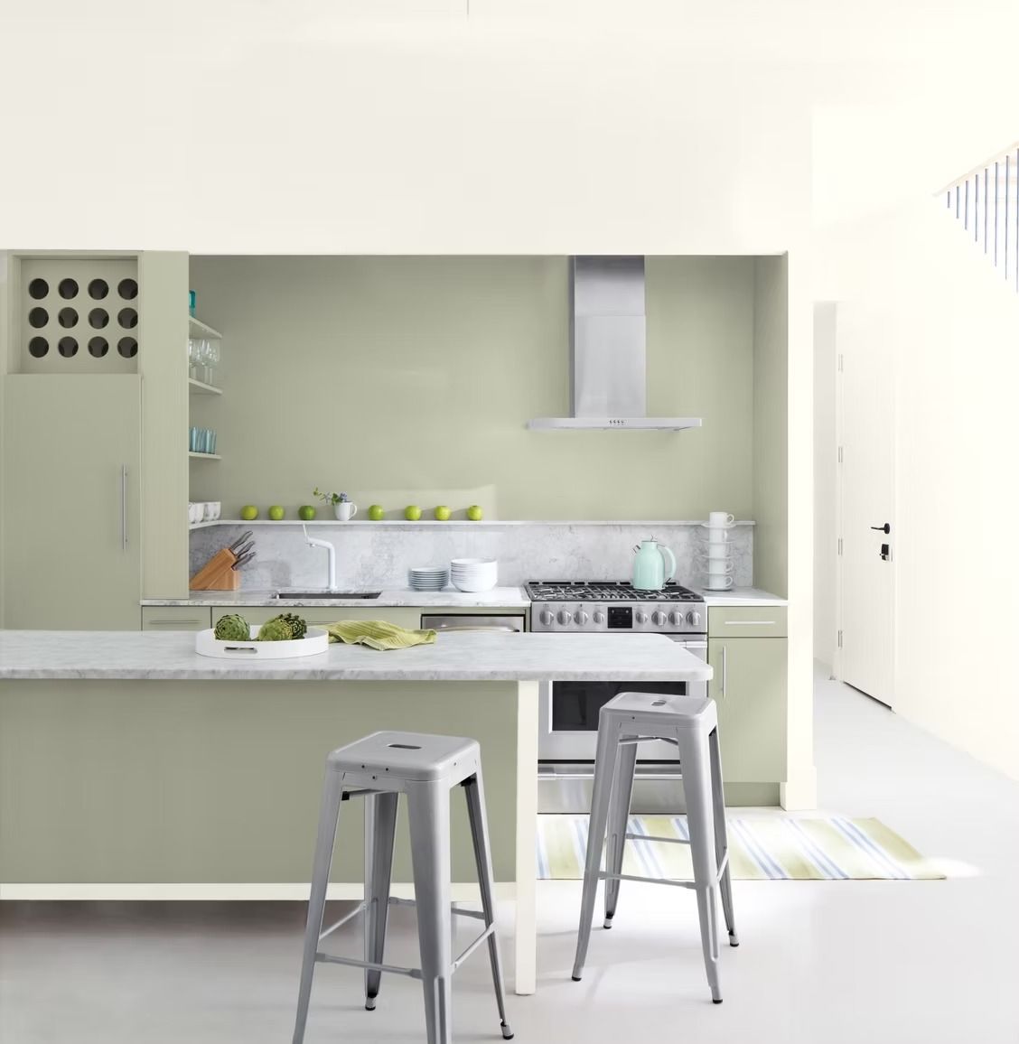 Modern white kitchen with two gray stools, island counter, stove, and range hood