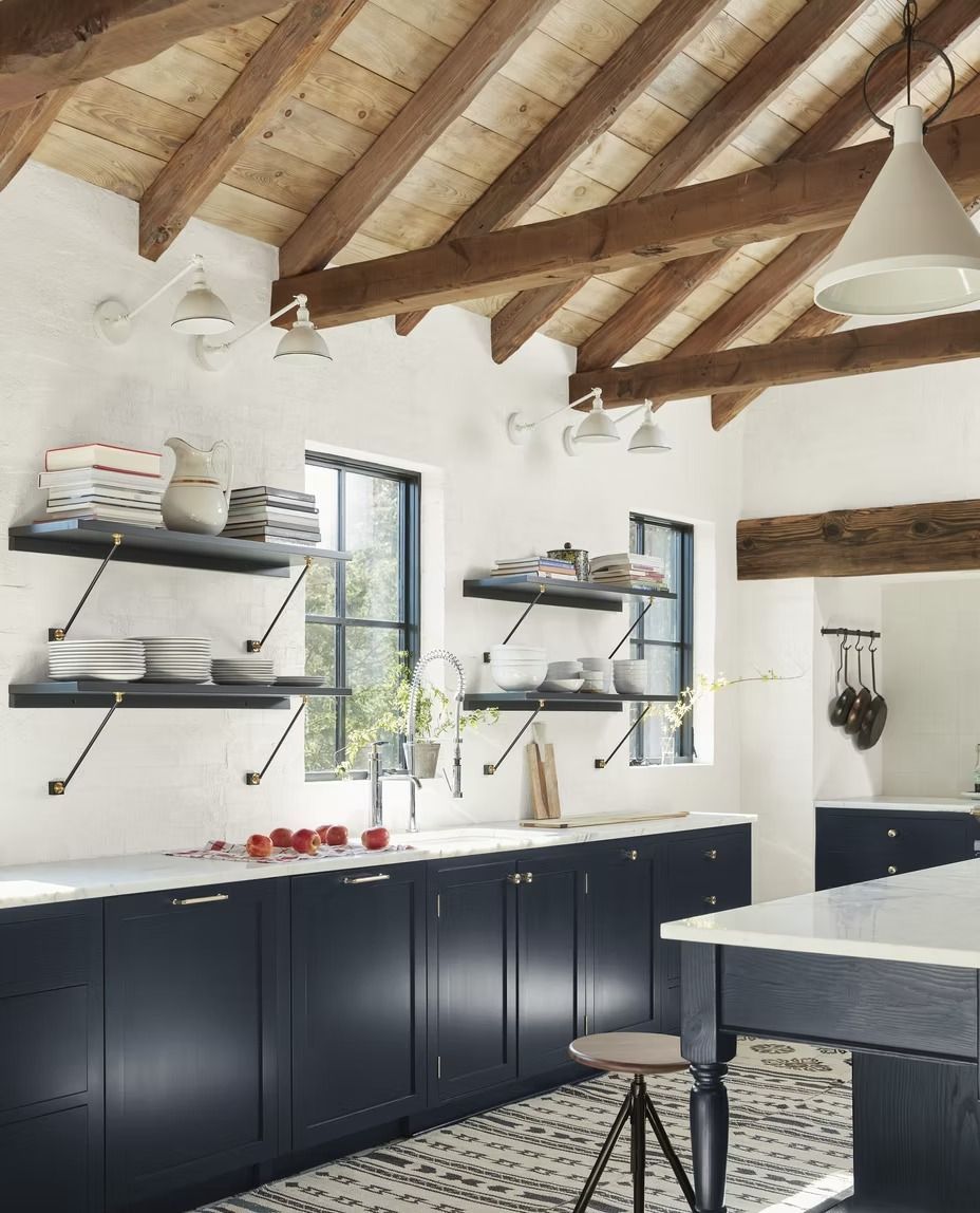 Bright kitchen with dark cabinets, white counters, open shelves, and exposed wood ceiling beams.