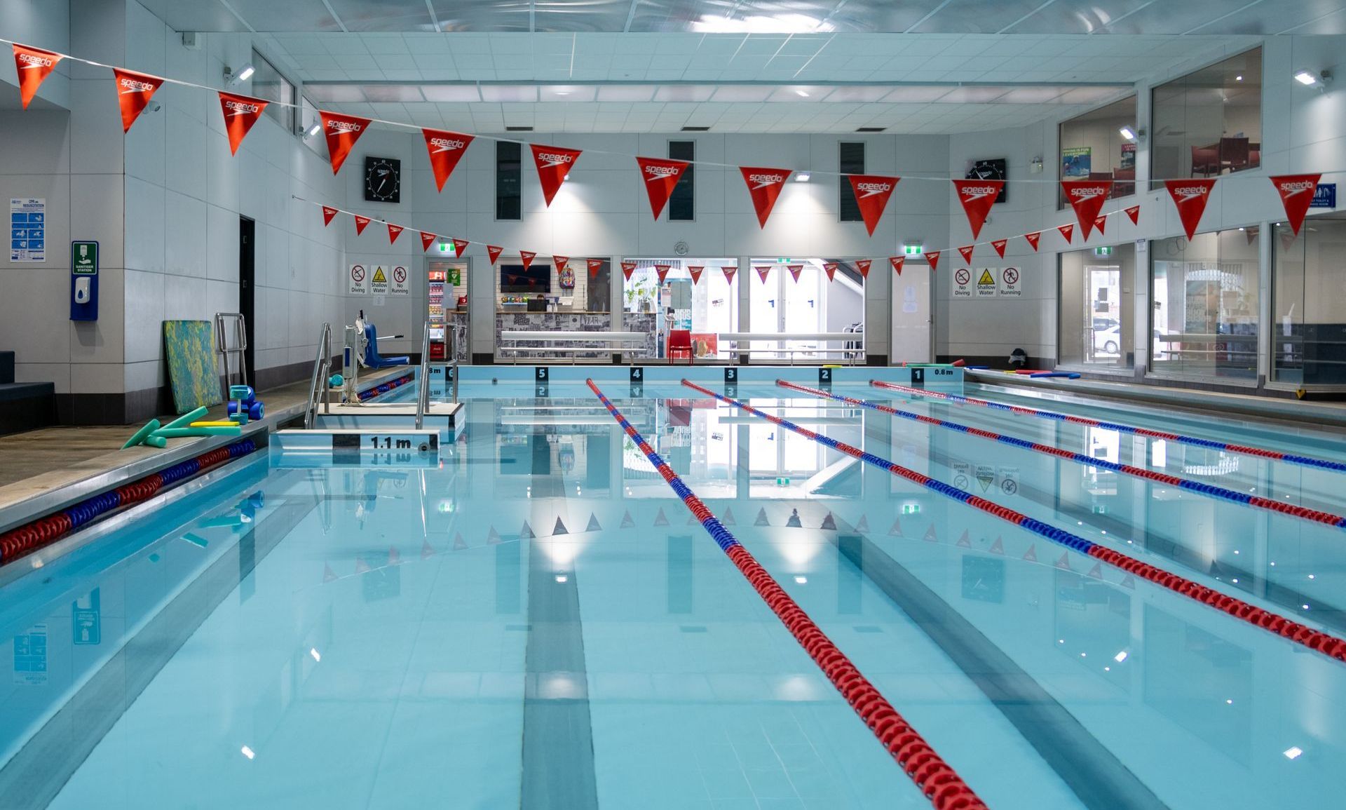 A large indoor swimming pool with red flags hanging from the ceiling.