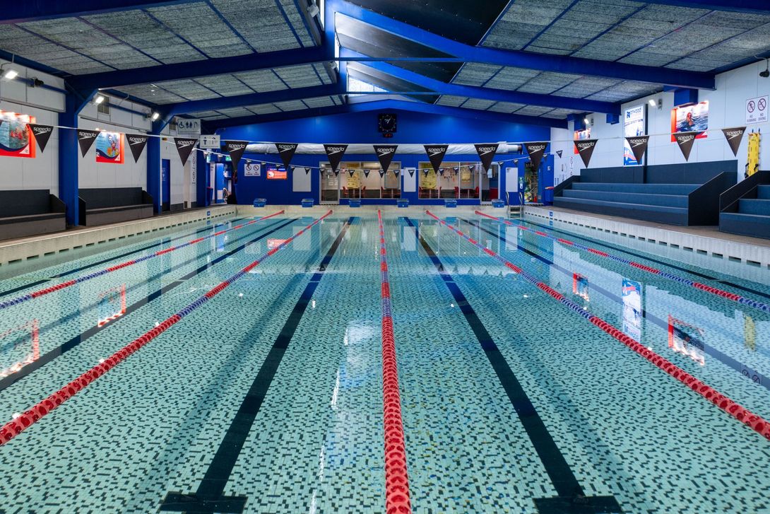 A large indoor swimming pool with red lanes in a gym.