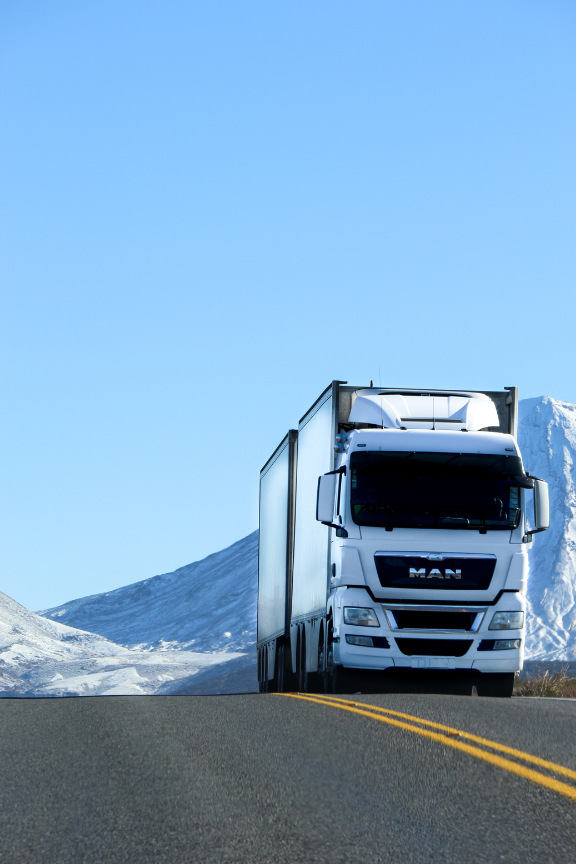 A man truck is driving down a snowy road
