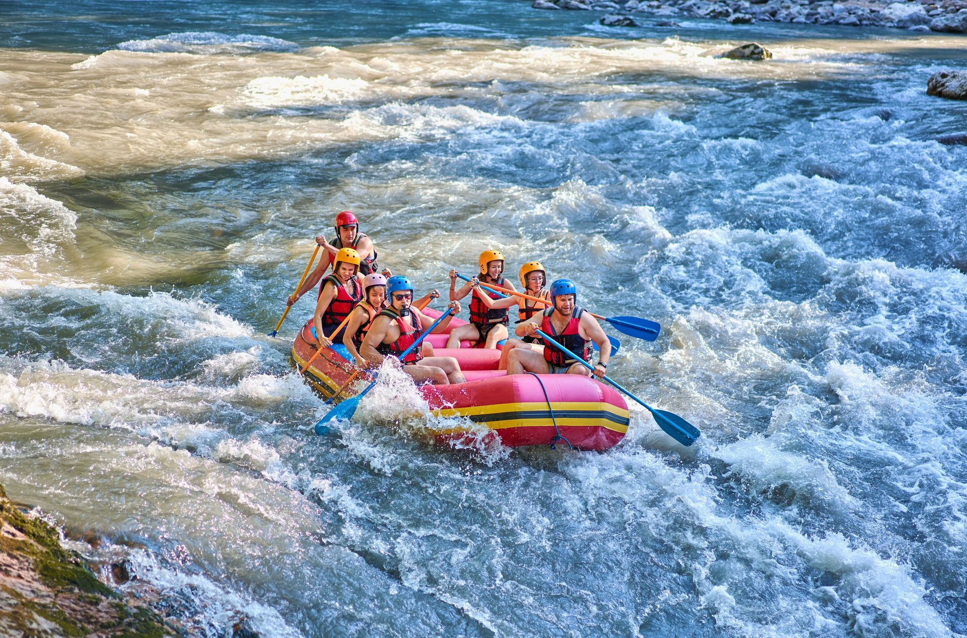 Rafting group in a colorful inflatable raft racing through choppy whitewater rapids
