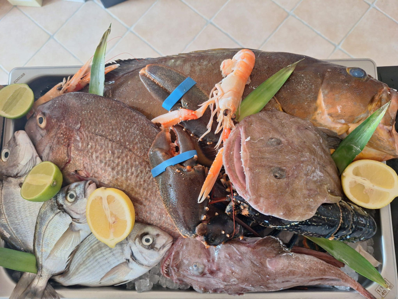 Piatto di frutti di mare con pesce intero, granchio, aragosta, calamari e spicchi di limone su un vassoio