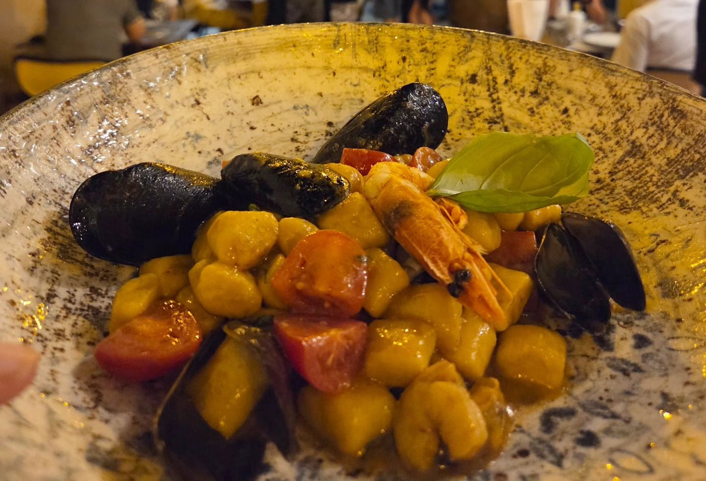 Piatto di gnocchi con cozze e basilico in un ambiente da ristorante
