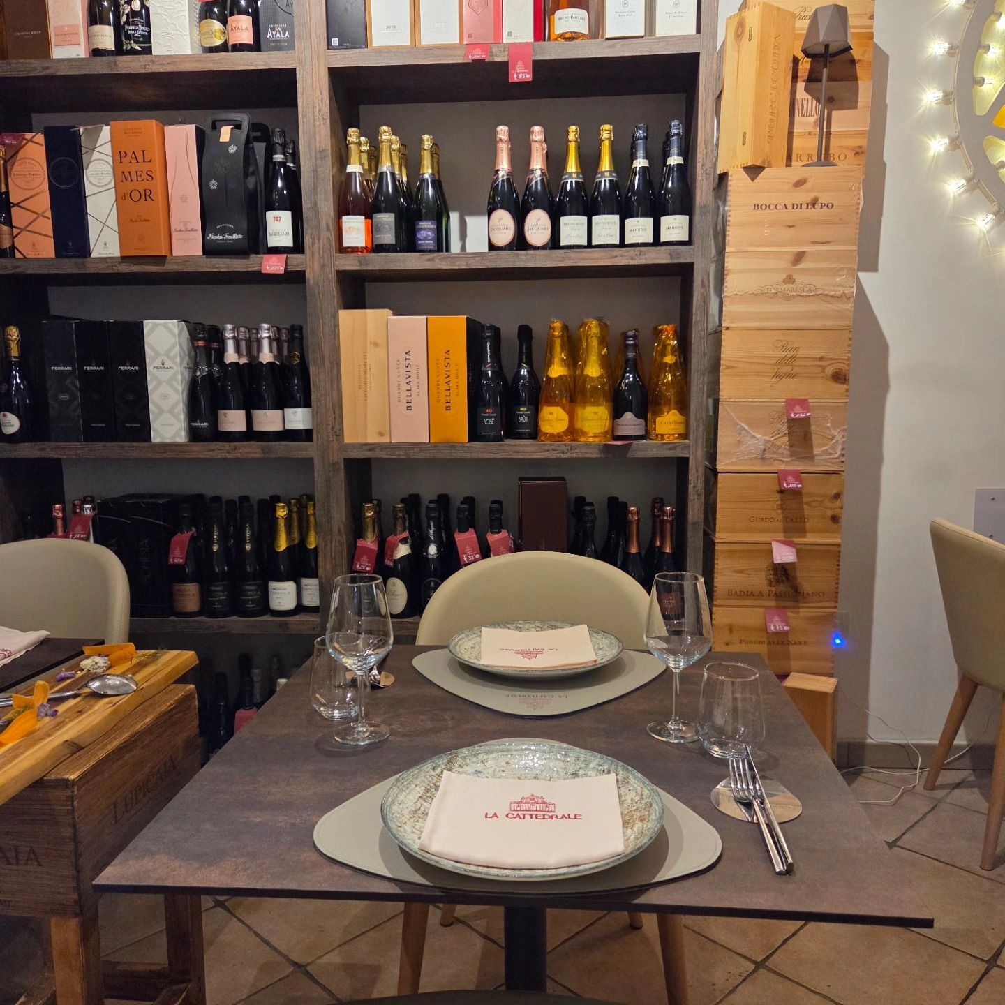 Accogliente angolo pranzo in cantina con tavolo apparecchiato, portabottiglie e luci soffuse.