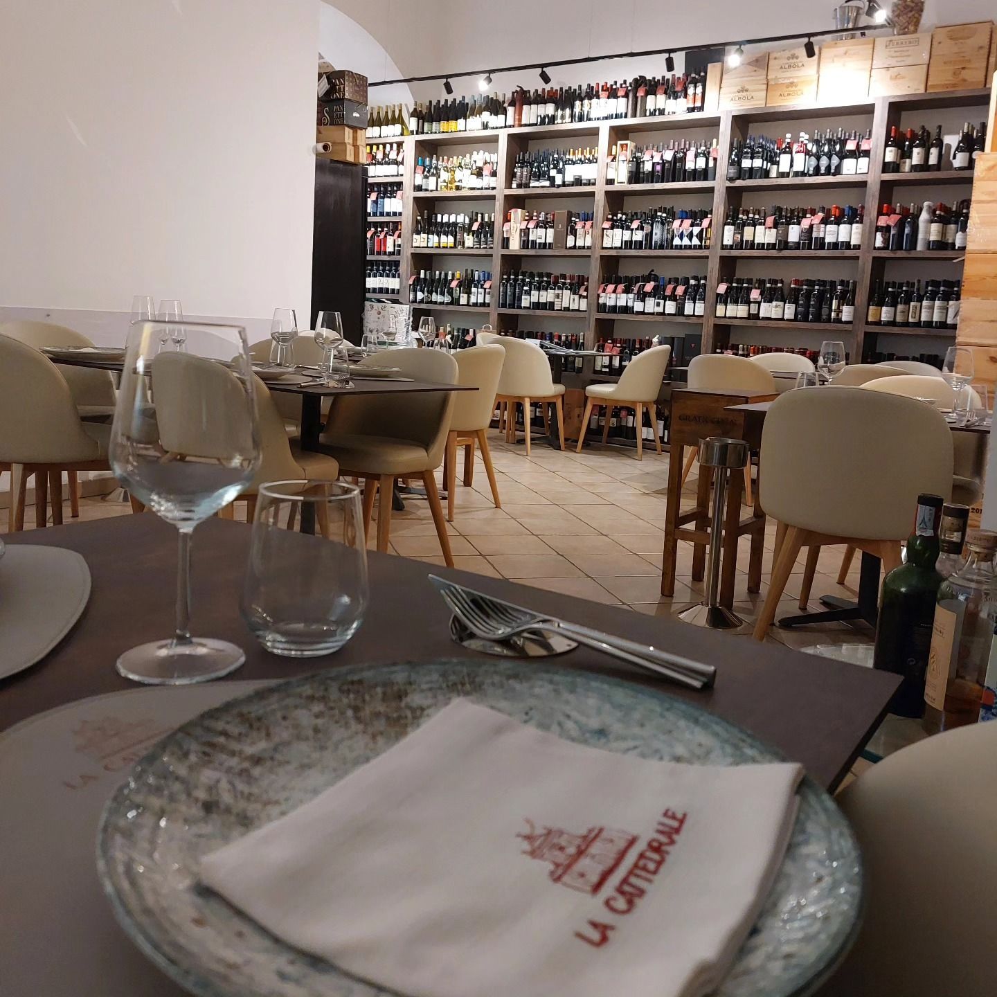 Accogliente sala da pranzo del ristorante con tavoli apparecchiati e una scaffalatura di vini ben fornita sullo sfondo.