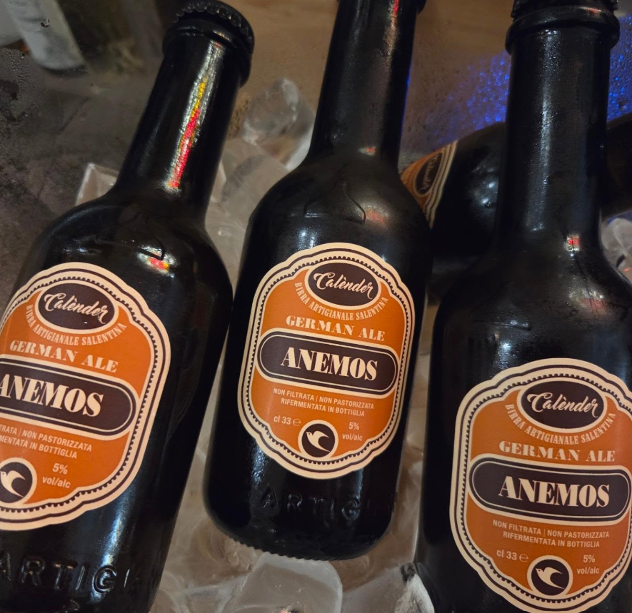 Tre bottiglie di birra scura con etichette arancioni con la scritta