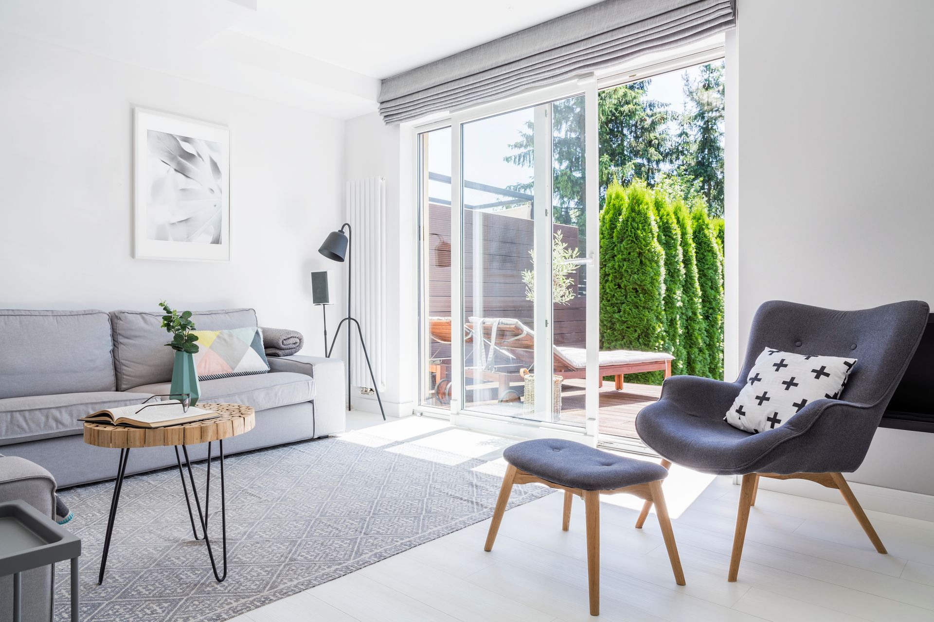 Bright modern living room with gray sofa, chair, and open sliding doors to a sunny patio.