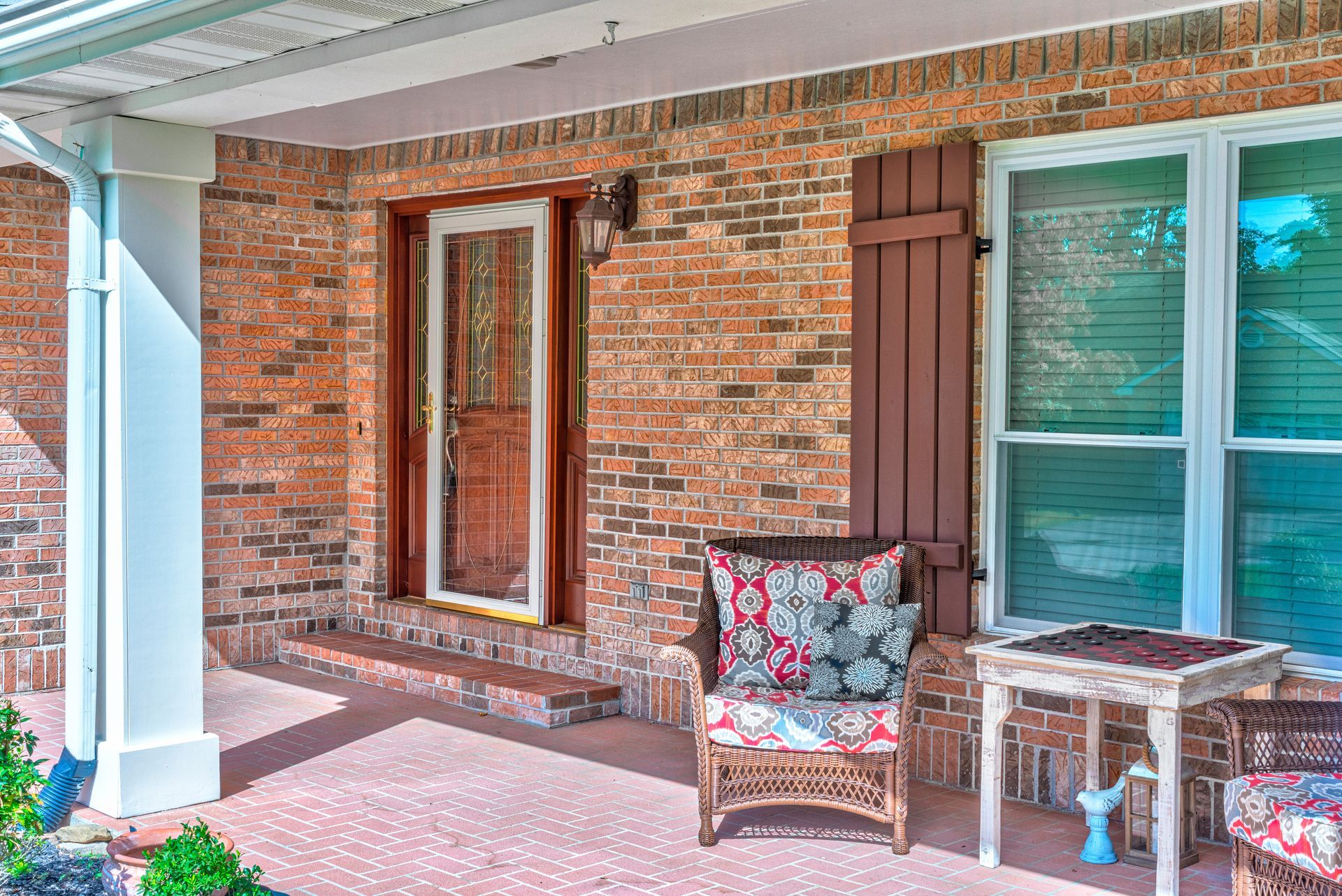 Front porch with a white door, brick wall, railing, and a hello doormat under a covered entry. Front porch with a white door, brick wall, railing, and a hello doormat under a covered entry.