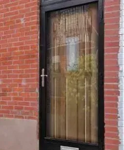 Glass-paneled black door set in a red brick wall with beige lower trim Glass-paneled black door set in a red brick wall with beige lower trim