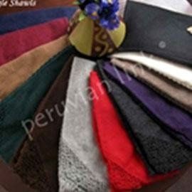 Assorted shawls in various colors arranged in a circular pattern. Some shawls are draped, while others appear folded.