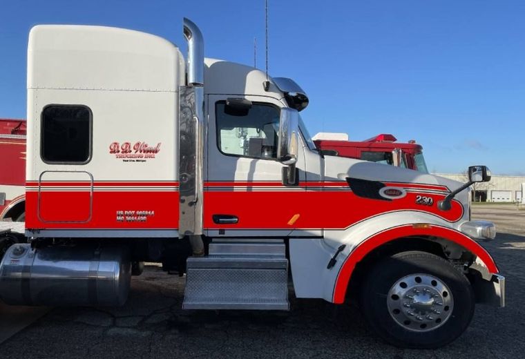 Red and white semi-truck cab parked outdoors under a clear blue sky