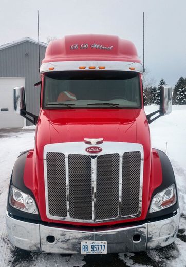 Front view of a red semi-truck parked in snow outside a building