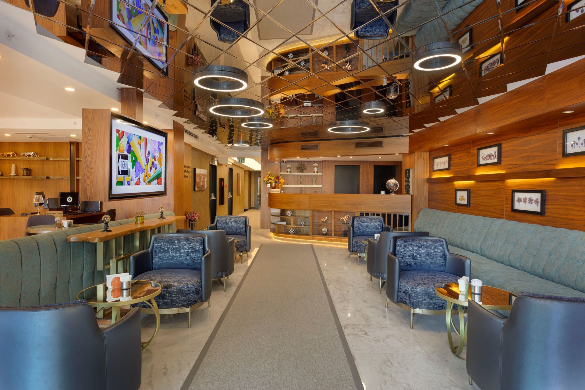 Mavi sandalyeler, ahşap bar, asılı halka lambalar ve renkli duvar sanatıyla dekore edilmiş modern bir salon.