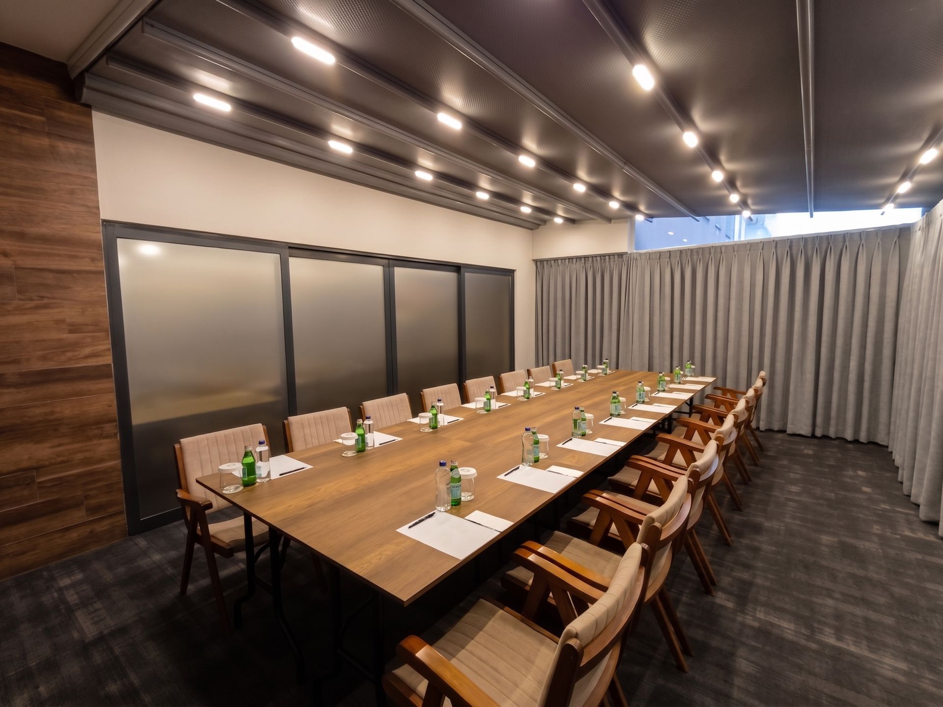 Izz Hotel Koşuyolu | İstanbul |Empty conference room with long wooden table, tan chairs, and recessed ceiling lights
