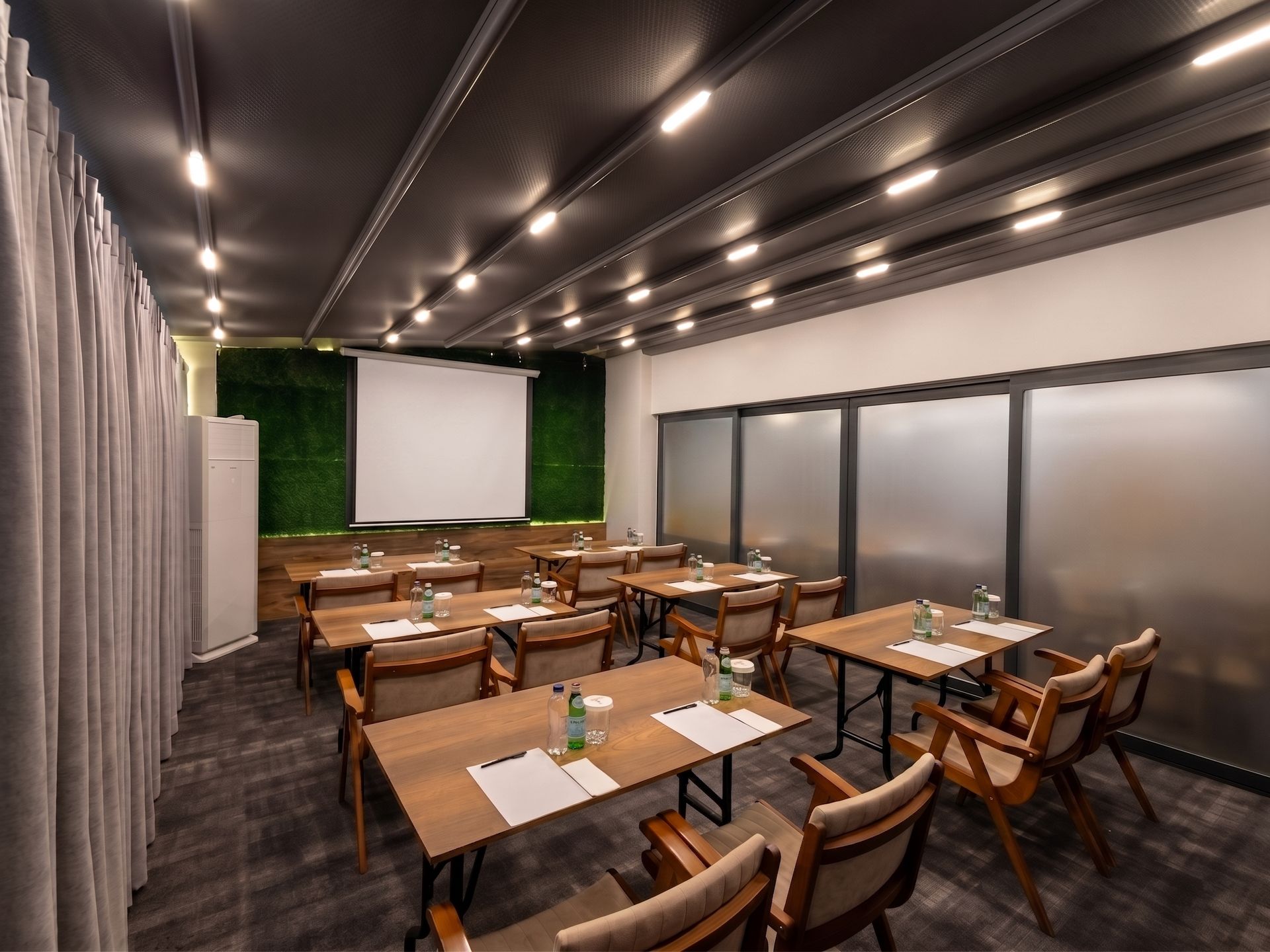 Izz Hotel Koşuyolu | İstanbul | Empty modern conference room with tables, chairs, projector screen, and frosted glass walls