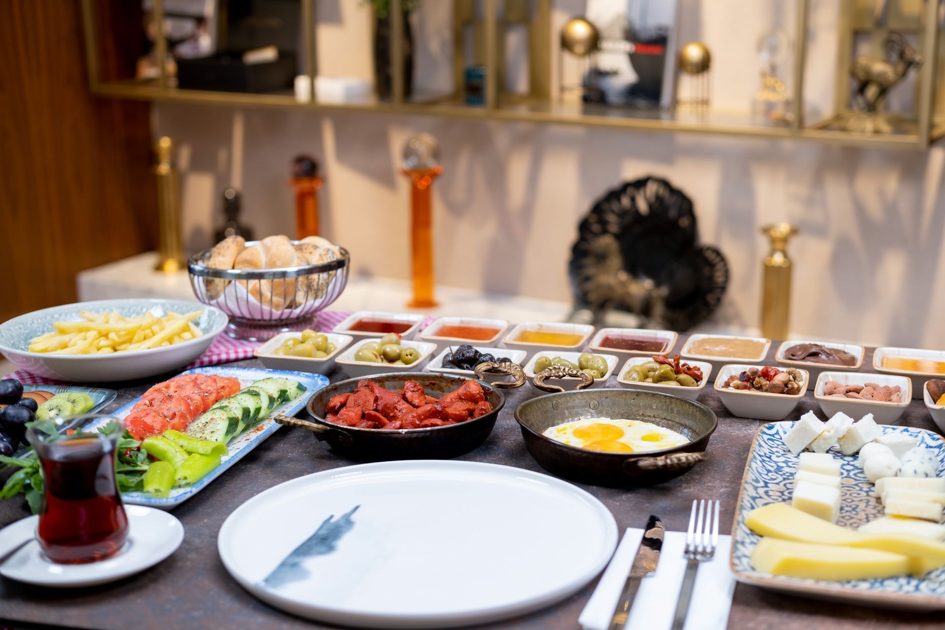 Yemek odasında, çeşitli yemekler, tabaklar ve çatal bıçak takımlarıyla donatılmış açık büfe masası.