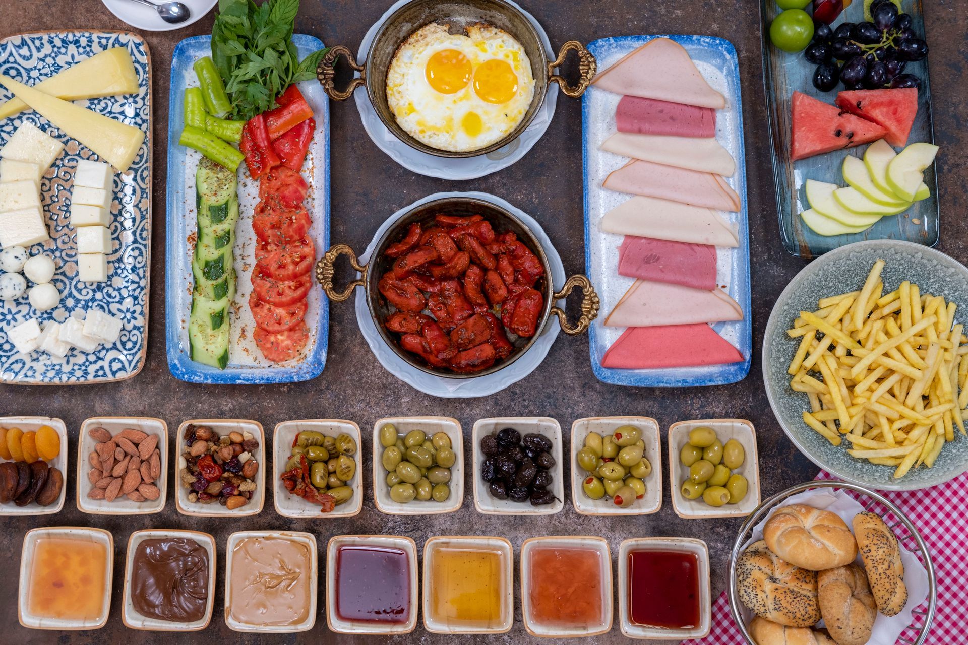 Suşi, kızarmış pilav, patates kızartması, ekmek, tatlı büfeleri, meyve ve küçük sos kaplarıyla rengarenk bir açık büfe.
