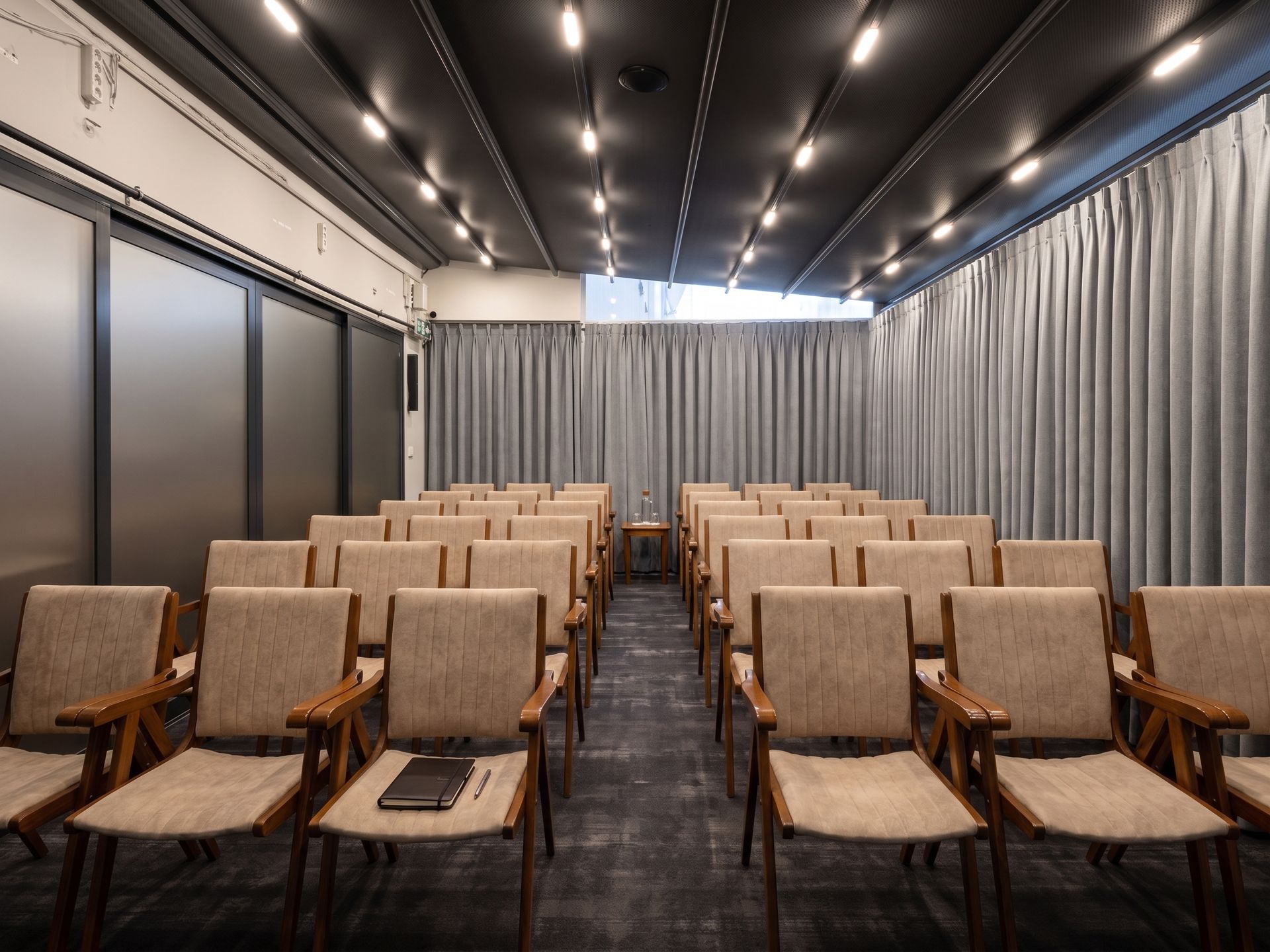 Izz Hotel Koşuyolu | İstanbul | Empty conference room with rows of tan chairs, gray curtains, and recessed ceiling lights