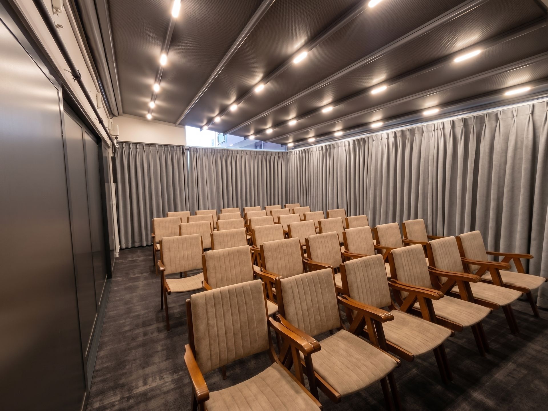 Izz Hotel Koşuyolu | İstanbul |Empty theater with rows of beige seats and gray curtains in a dimly lit room