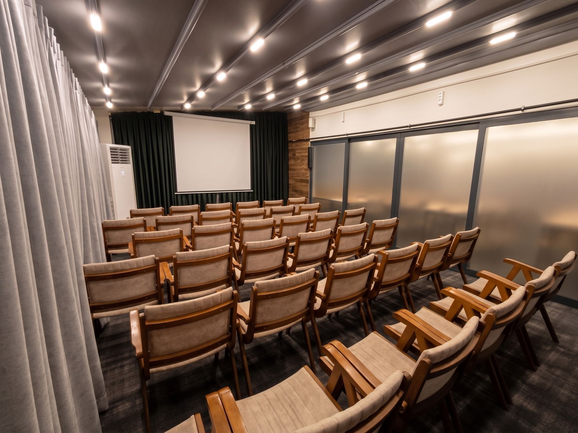 Izz Hotel Koşuyolu | İstanbul | Empty conference room with rows of wooden chairs facing a projection screen and windows.
