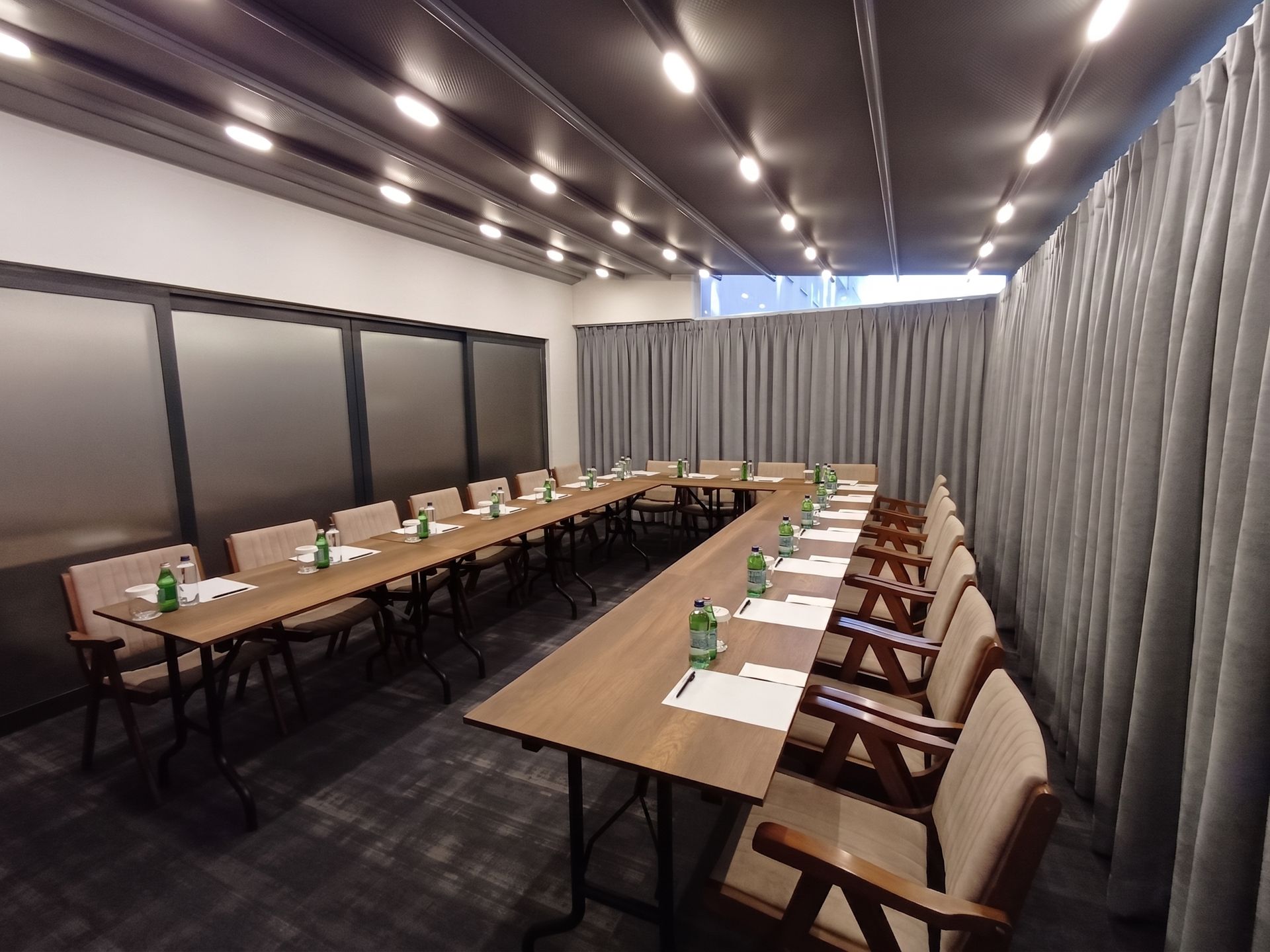 Izz Hotel Koşuyolu | İstanbul |Conference room with long tables, beige chairs, and gray curtains under bright ceiling lights