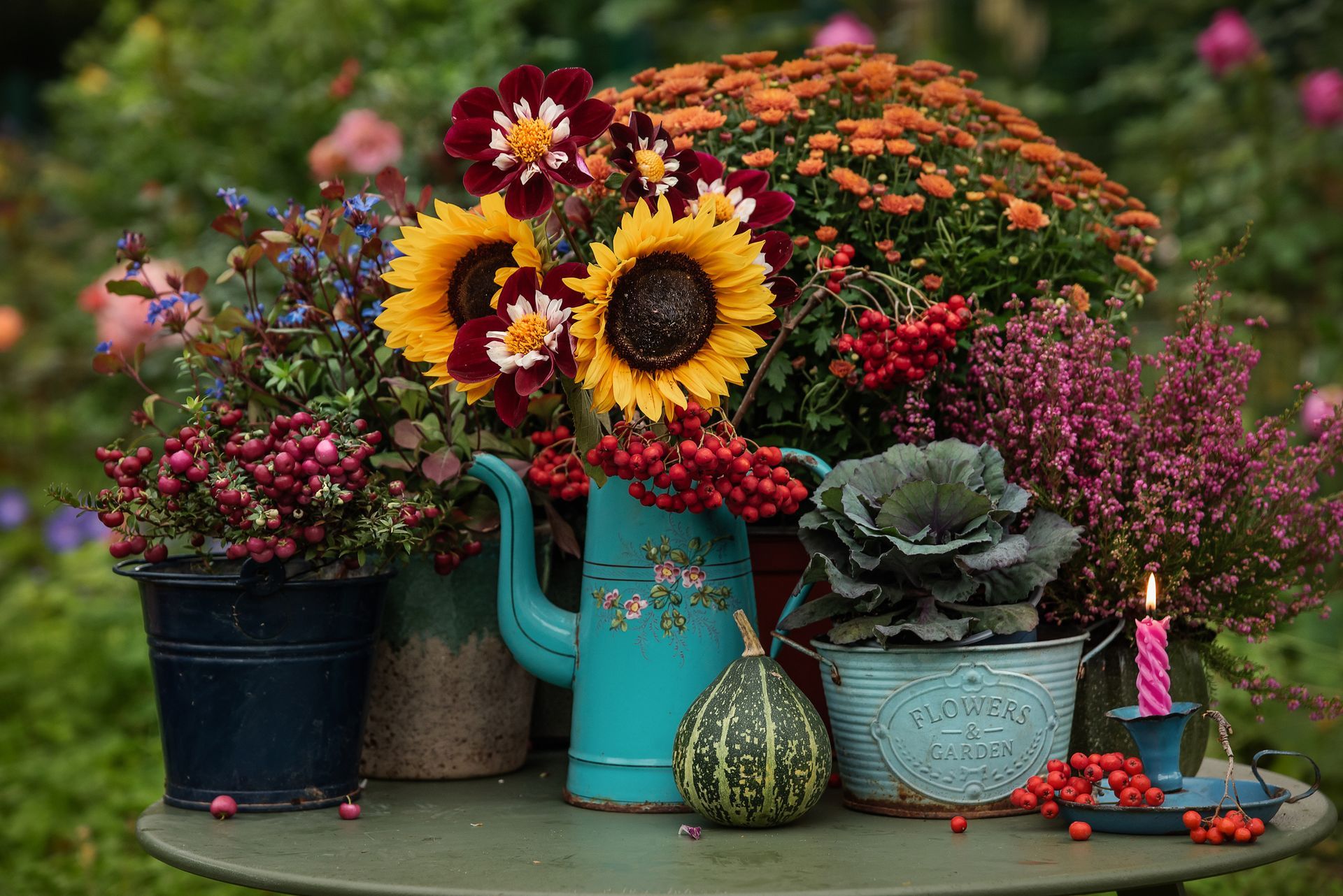 Assorted colorful flowers in pots and watering cans arranged on a garden table