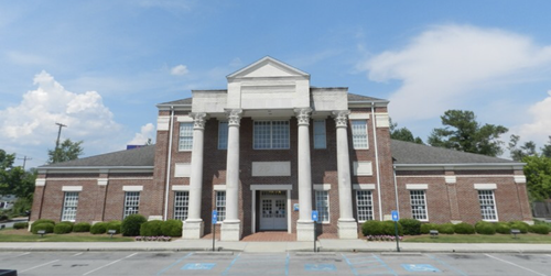 A large brick building with columns and a parking lot in front of it