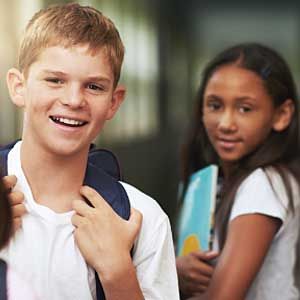 A boy and a girl are standing next to each other in a hallway.