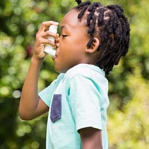 A young boy is using an inhaler to treat his asthma.
