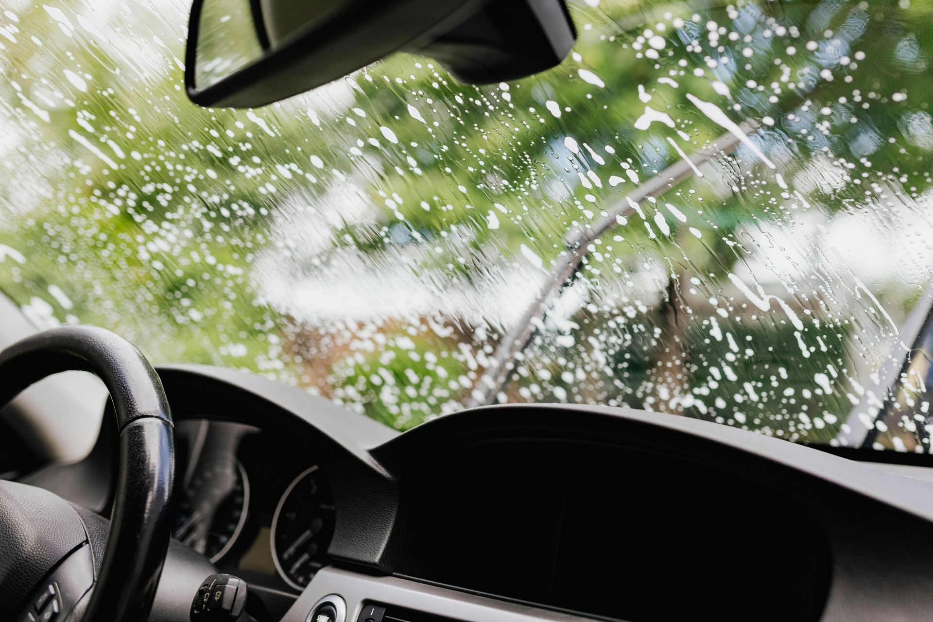 Cracked car windshield with shattered glass and rain, viewed from the driver’s seat