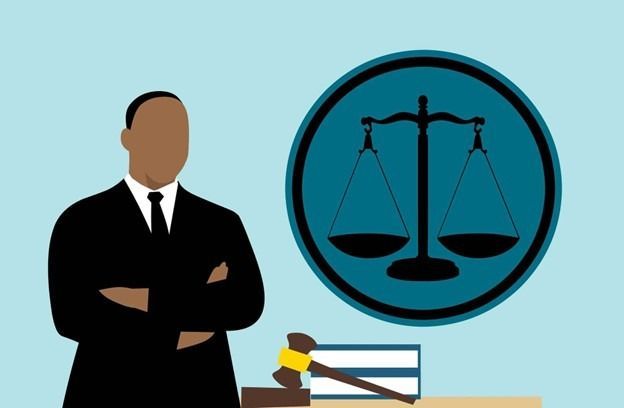 A person in a suit standing before a gavel, books, and a circular icon displaying scales of justice.