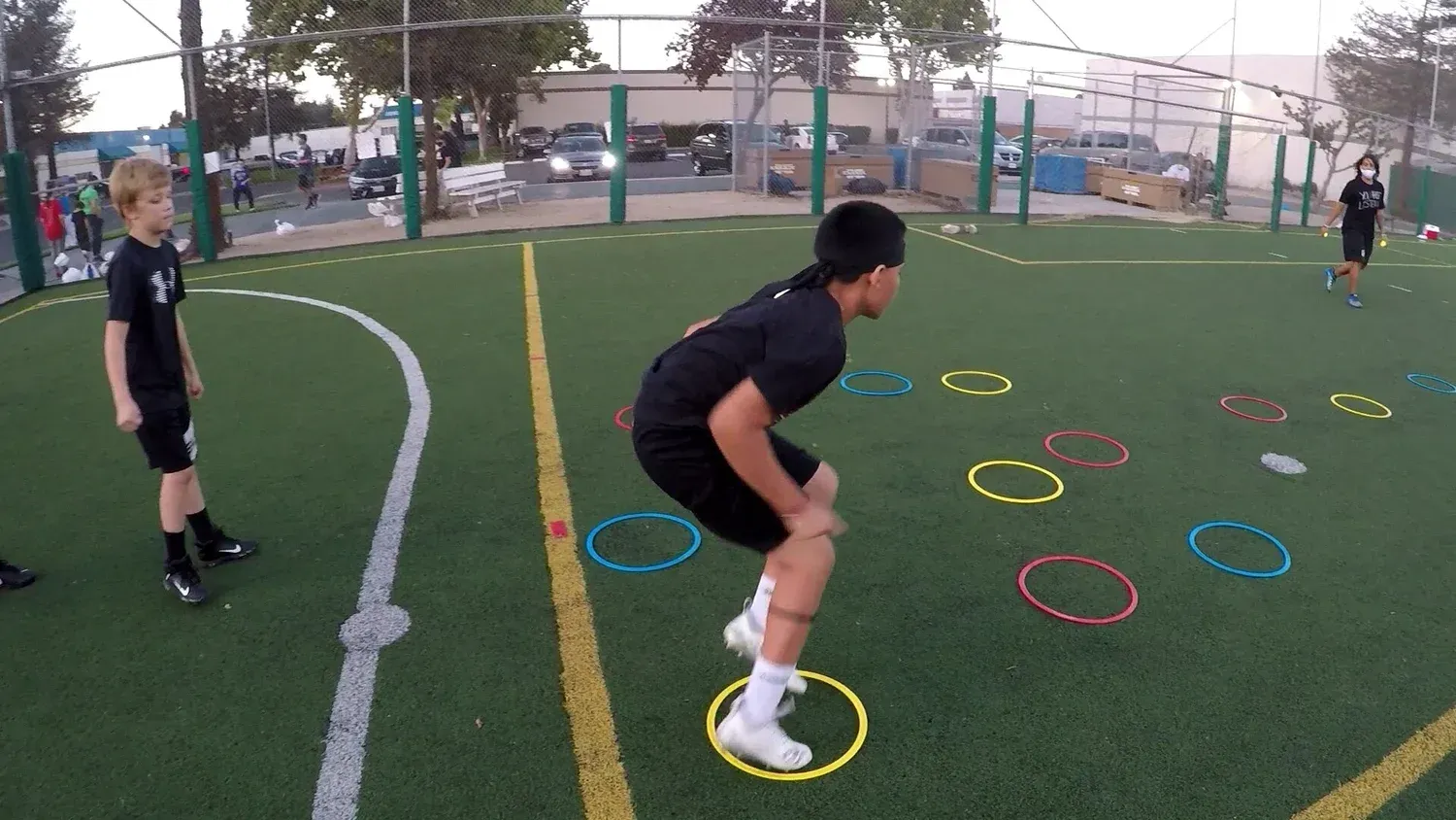 Athletes doing agility drills on colored rings on an outdoor turf field