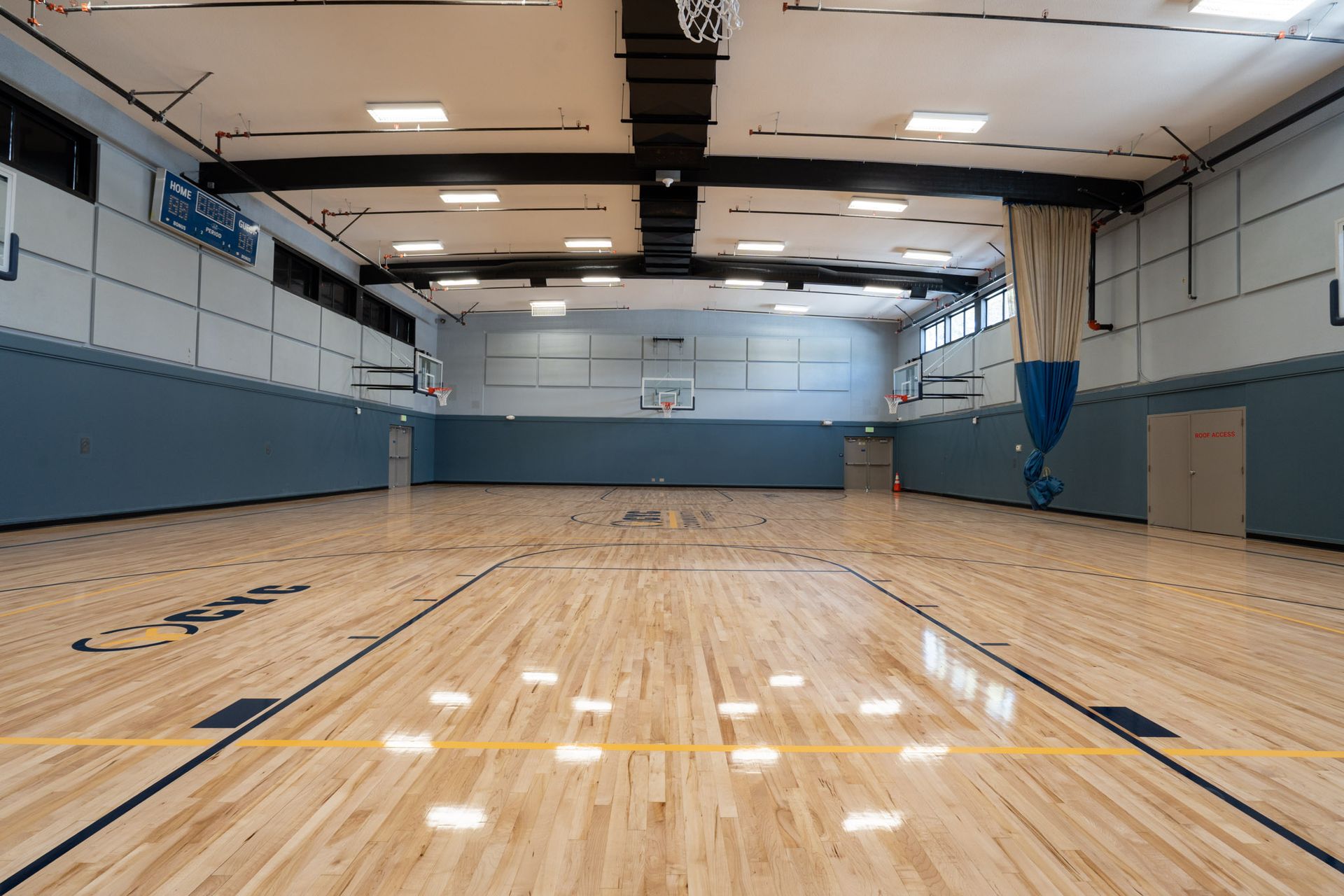 Empty indoor basketball gym with a polished wooden court and blue padded walls