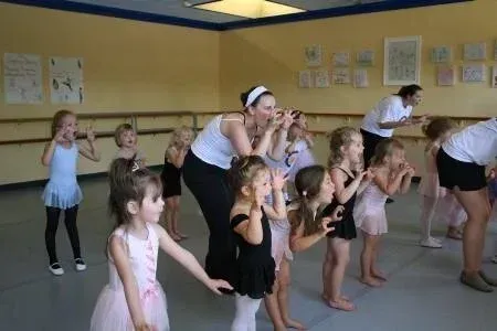Dance class with children and instructors practicing movements in a studio