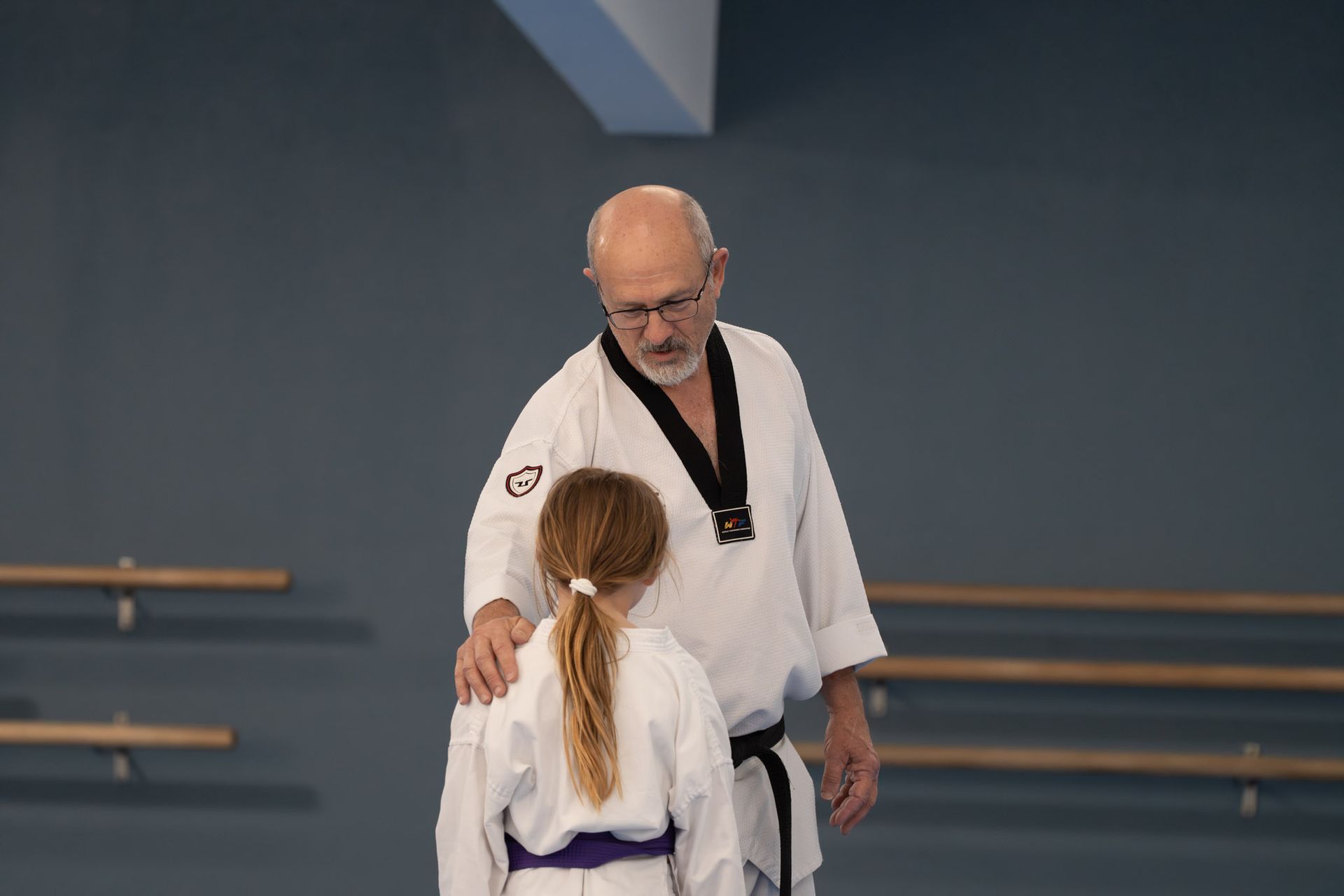 Martial arts instructor in white gi speaking to student in dojo