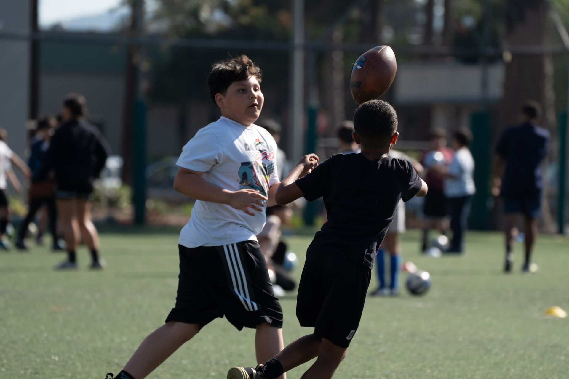 Two boys reaching for a football during a game on a grassy field