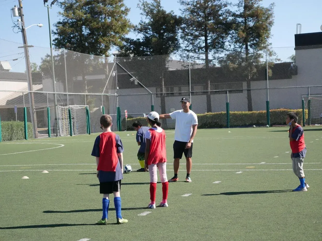 Children and coach on a soccer field, standing near the ball during practice