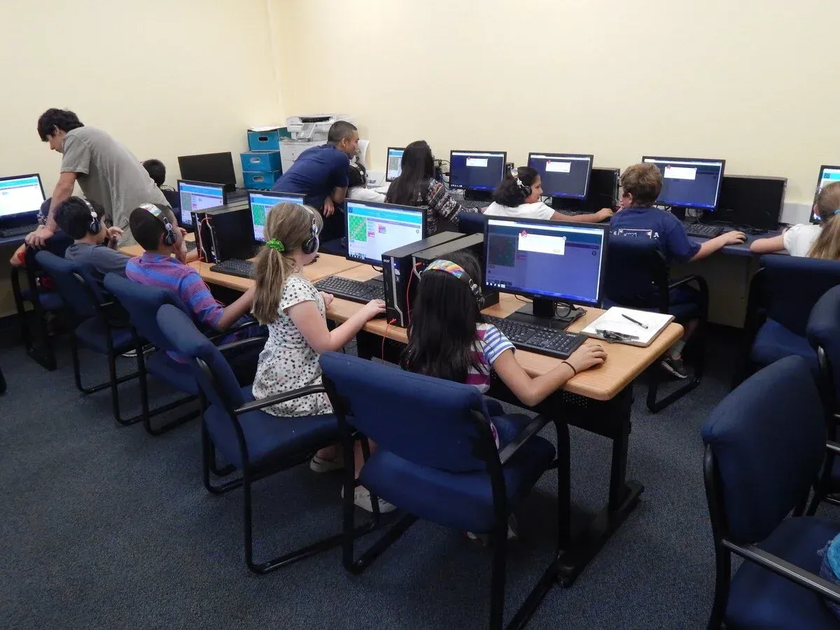 People seated at desktop computers in a computer lab, working on a lesson.