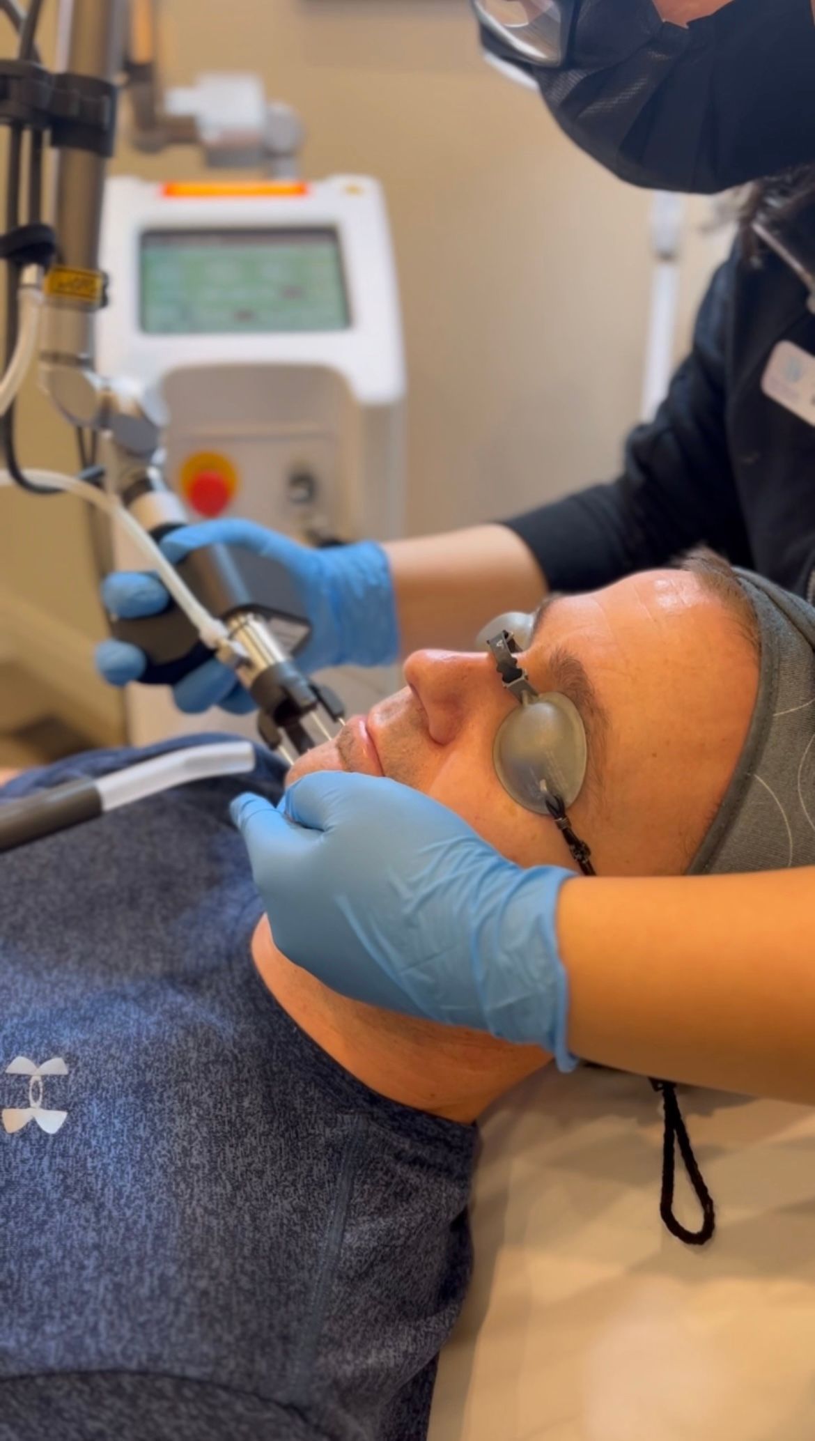 Dentist treating a reclining patient with dental tools and blue gloves in a clinic.