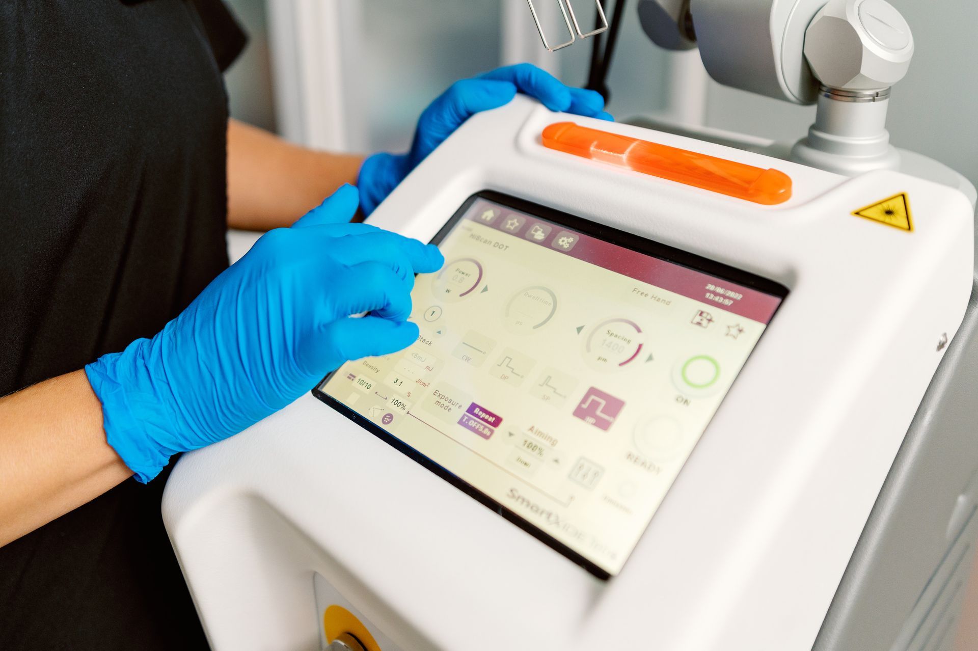 Gloved hand using a touchscreen medical device with a robotic arm attached