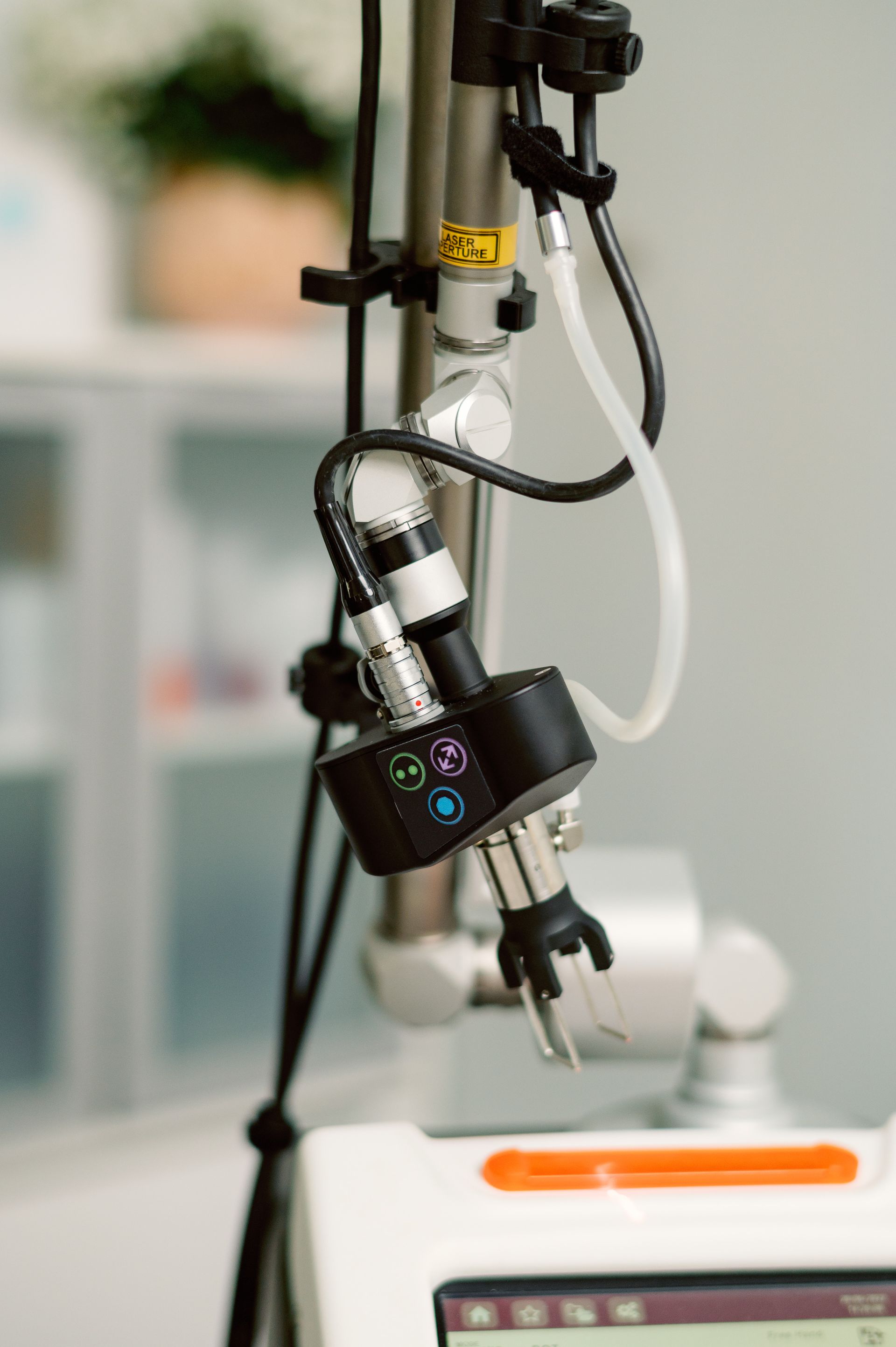 Medical robotic arm with tubes and wires over a lab device in a clinical setting