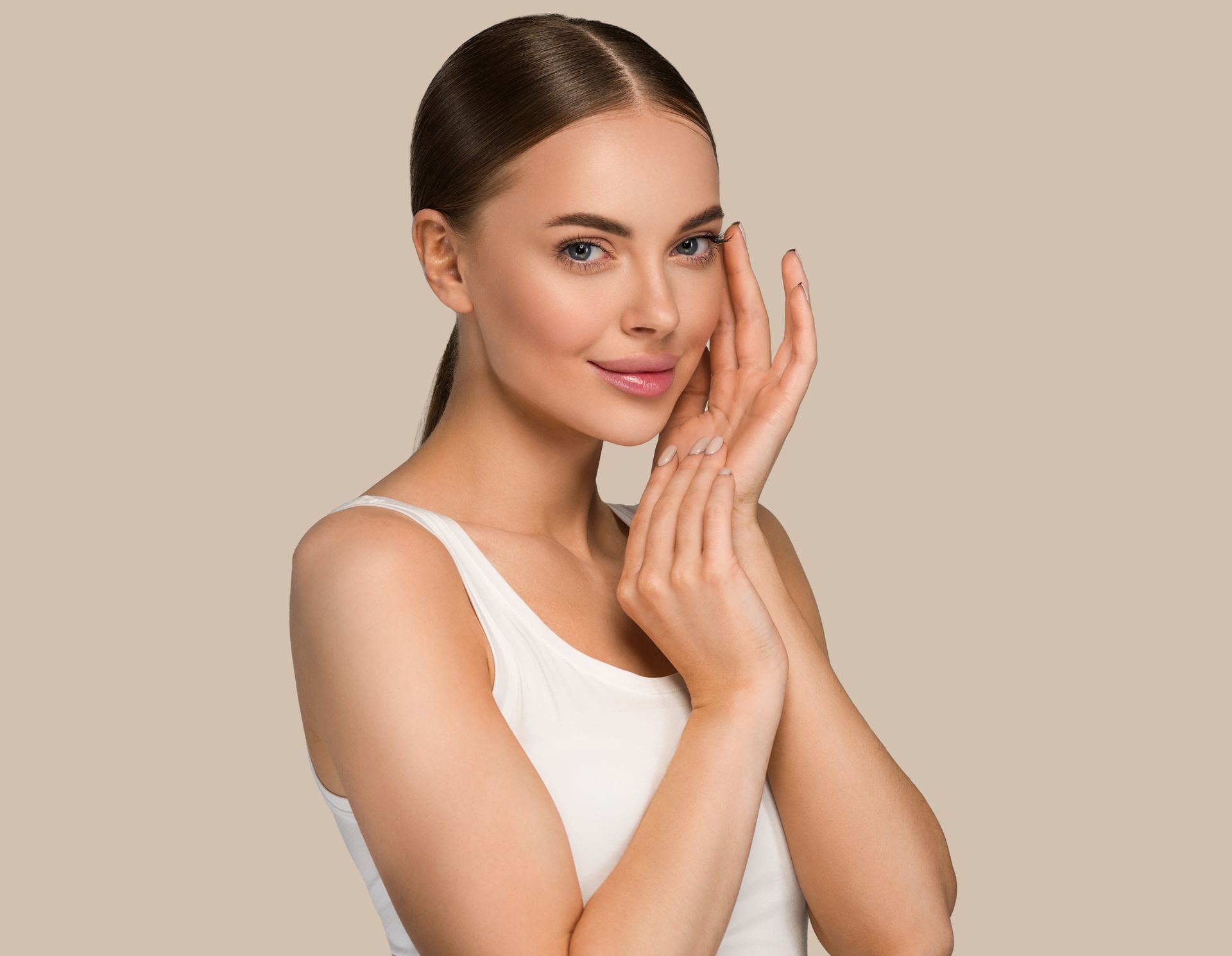 A woman is touching her face with her hands and smiling.