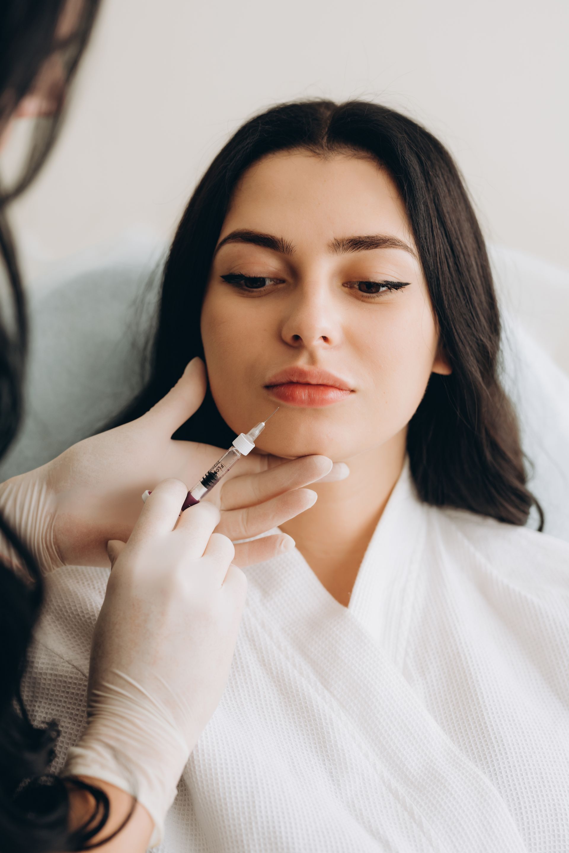 A woman is getting a filler injection in her face.