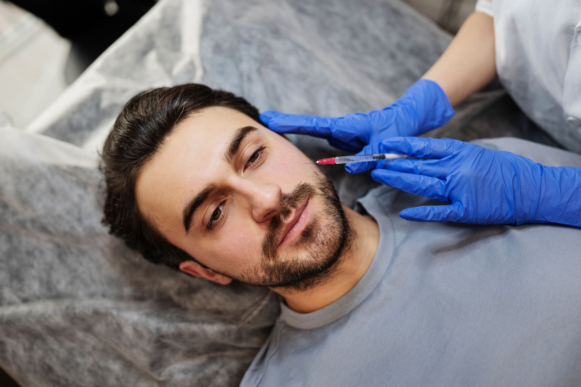 A man with a beard is getting a botox injection in his face.