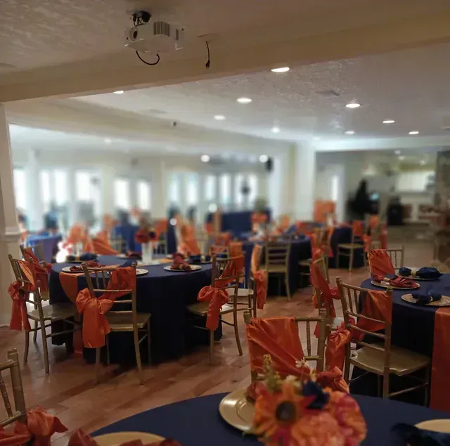 A large room with tables and chairs set up for a wedding reception.