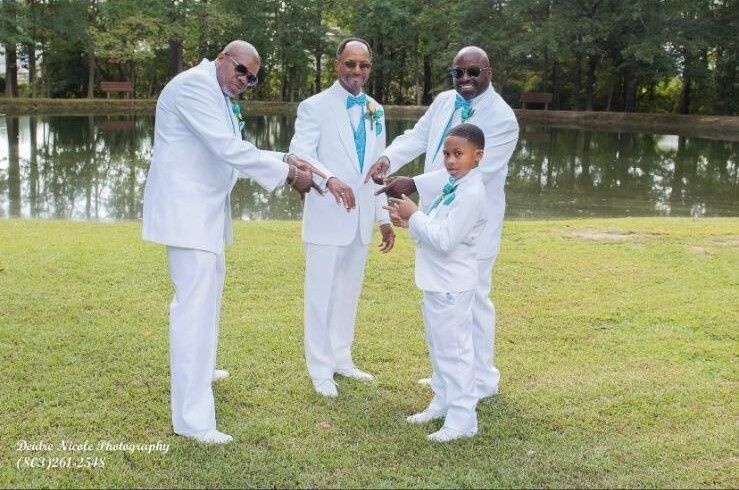 A group of men in white suits shaking hands with a boy